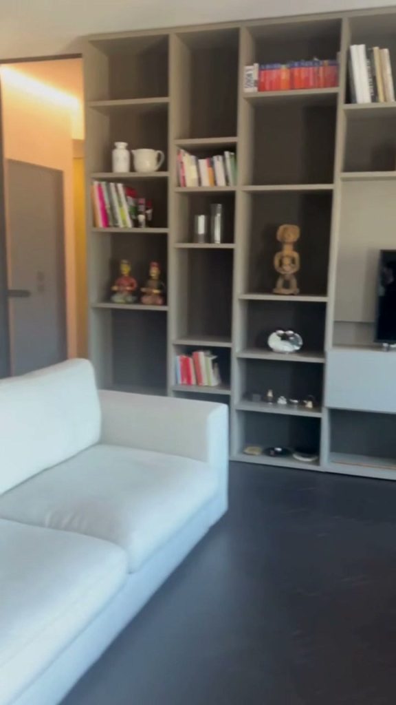 Parquet con finitura in microresina scuro nel soggiorno con divano bianco e libreria a tutta altezza